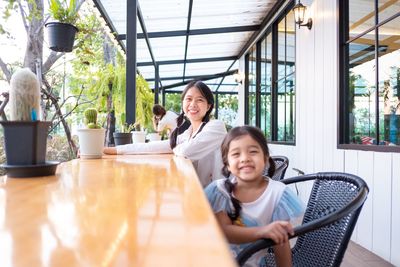 Portrait of smiling mother with daughter sitting at restaurant