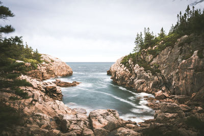 Scenic view of rocks by sea against sky