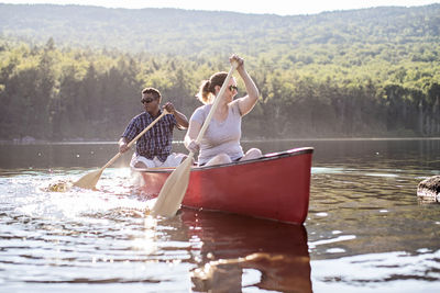 African male and white female couple paddle boat on beautiful pond