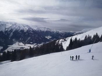 People skiing on snowcapped mountain against sky