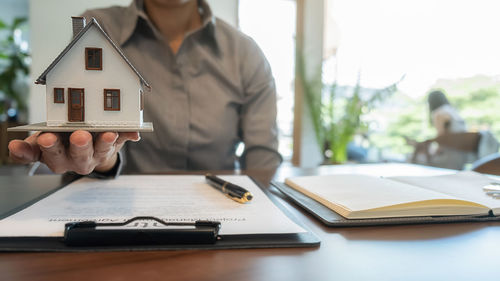 Midsection of man holding model house in office