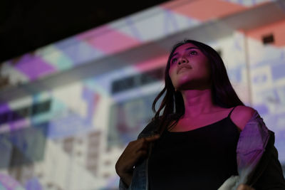 Woman looking away while standing outdoors