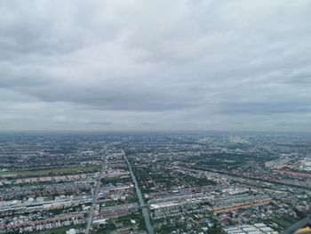 High angle view of city buildings against cloudy sky