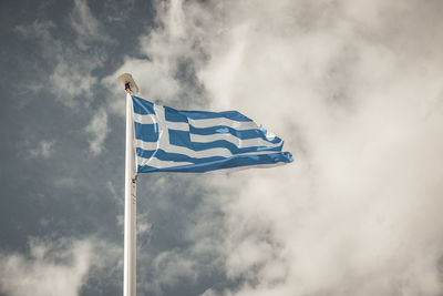 Waving greek flag against a blue sky with clouds. muted colors.