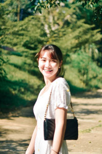 Portrait of young woman standing against waterfall