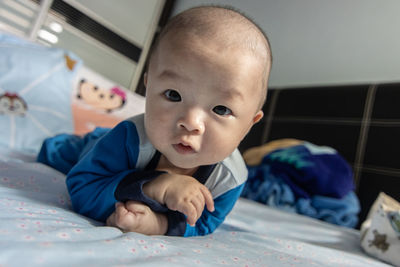 Portrait of cute baby lying on bed at home