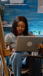 Young woman using phone while sitting on table