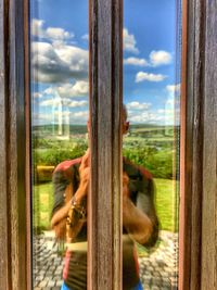 Reflection of man looking through glass window