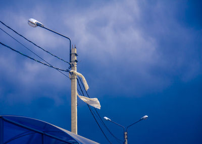 Low angle view of street lights against blue sky