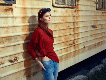 Portrait of young woman standing against wall