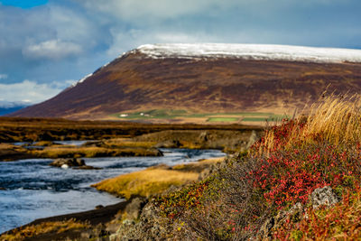 Scenic view of lake by snowcapped mountains against sky