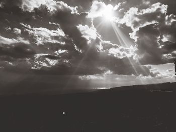 Sun shining through clouds in sky