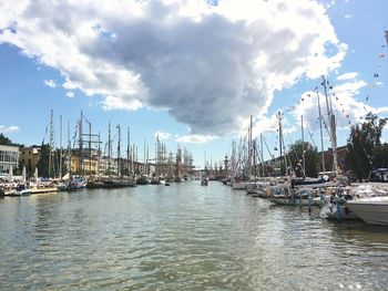 Sailboats moored on harbor in city against sky