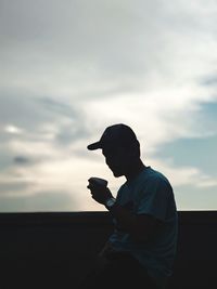 Side view of silhouette man standing against sky during sunset