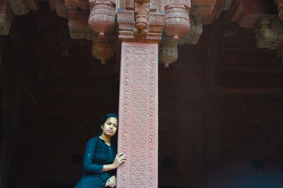 Thoughtful woman standing at temple