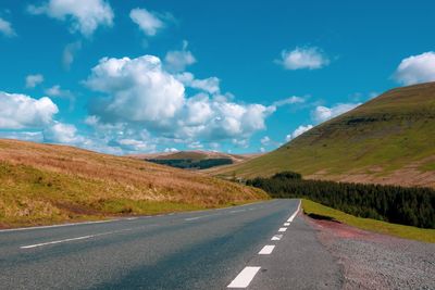 Empty road along landscape against sky