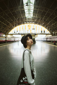 Side view portrait of woman standing at railroad station platform