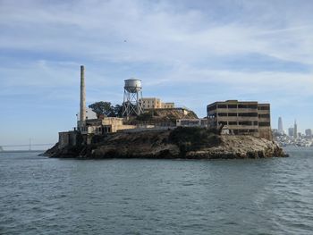 Buildings by sea against sky