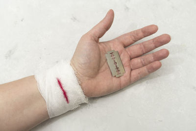 Cropped image of injured hand with razor blade on table