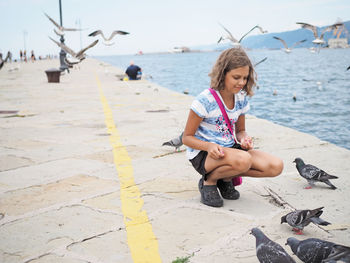 Girl feeding pigeons on promenade