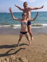 Happy dad and daughter jumping on the beach