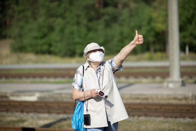 Woman holding umbrella while standing on field