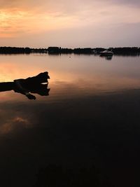 Silhouette boat in lake against sky during sunset