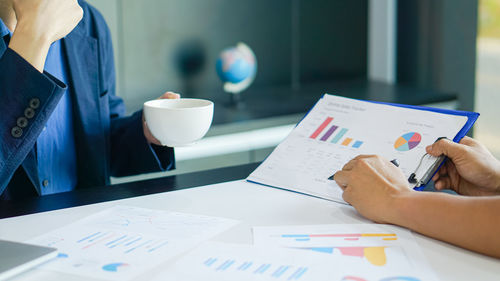Midsection of woman holding paper at table