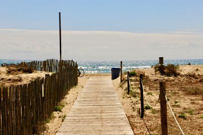 Wooden posts on beach against sky