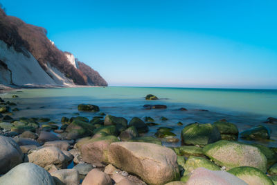 Rocks on beach against blue sky