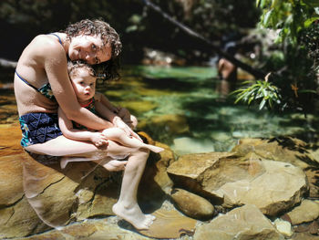 Mother and daughter cooling off in summer at waterfall.