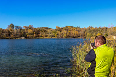 Rear view of man looking at sea against clear blue sky