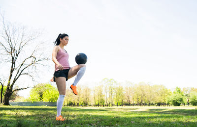 Full length of woman playing on field against sky