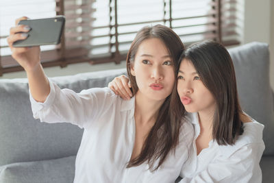 Portrait of young woman using mobile phone at home