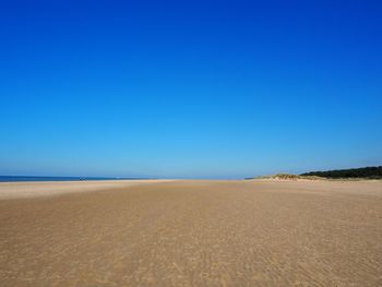 Scenic view of beach against clear blue sky