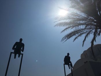 Low angle view of silhouette men against clear sky