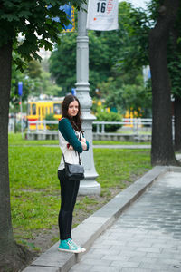 Full length portrait of woman standing on footpath