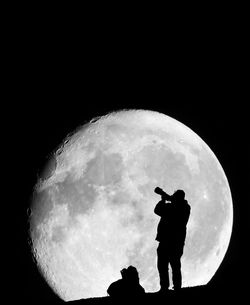 Silhouette man standing against moon at night