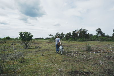 Rear view of men walking on field against sky