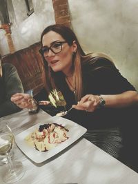 Portrait of a smiling young woman eating while sitting in city