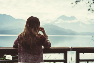 Rear view of woman looking at sea against sky during winter