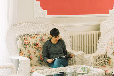 Woman reading magazine while sitting on sofa at home