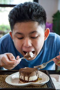 Boy eating cake while sitting at cafe