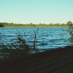 Calm lake against clear blue sky