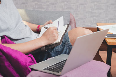 Midsection of woman using laptop while sitting on table