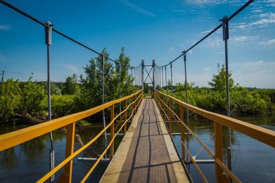 Footbridge over plants against sky