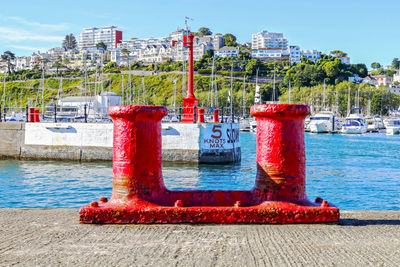 Red metallic bollard on pier at harbor