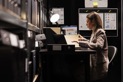 Rear view of woman using laptop at home