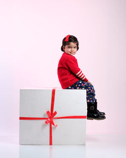 Young woman holding gift box against white background