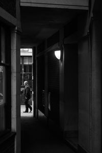 Side view of man walking in illuminated building at night